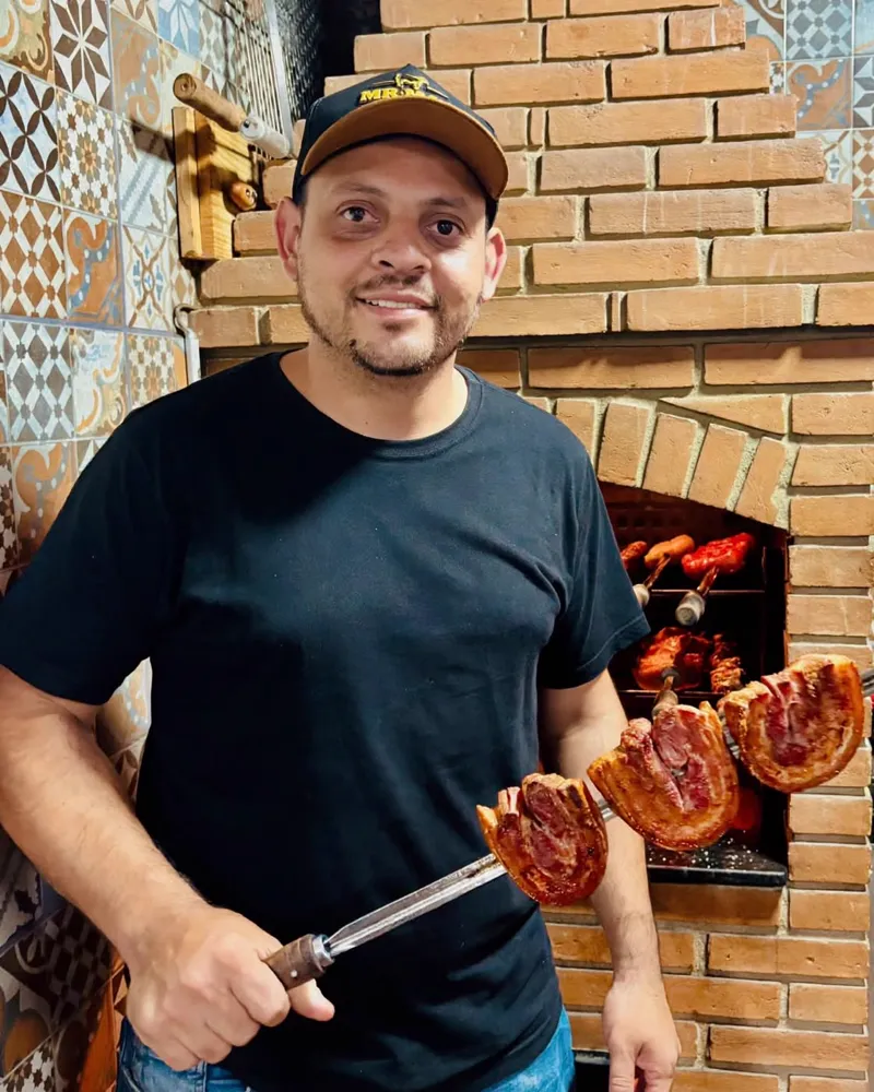 Caique com o espeto de picanha na churrasqueira